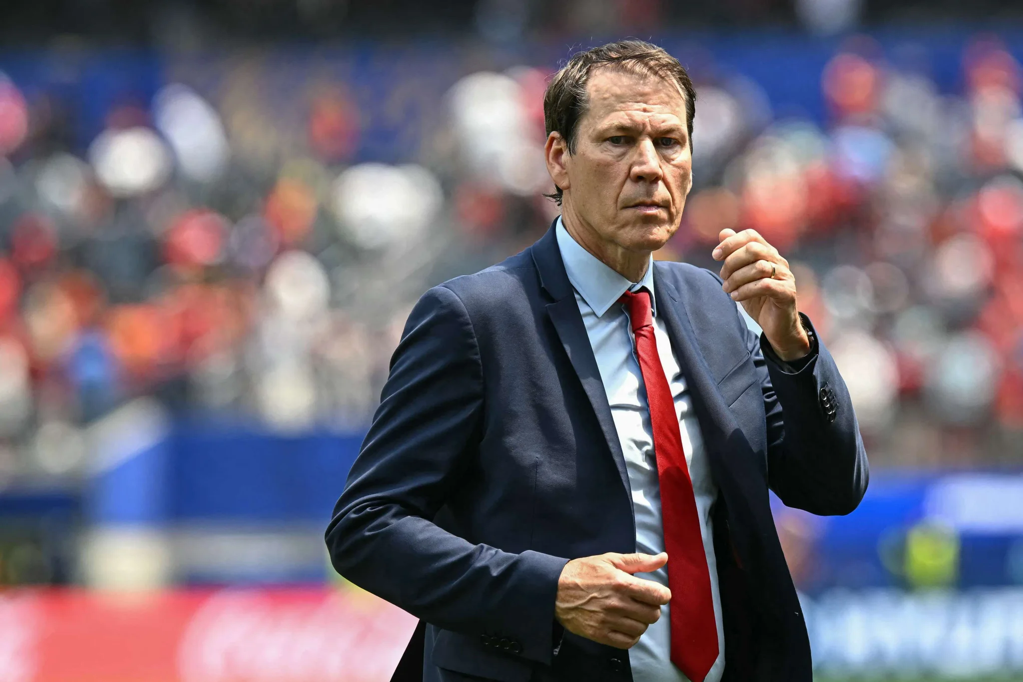 رودي غارسيا مدرب المنتخب البلجيكي السابق يرتدي بدلة وربطة عنق حمراء خلال مباراة في كأس العالم 2026، يعكس وداعه بعد 18 شهراً من قيادة الفريق.
