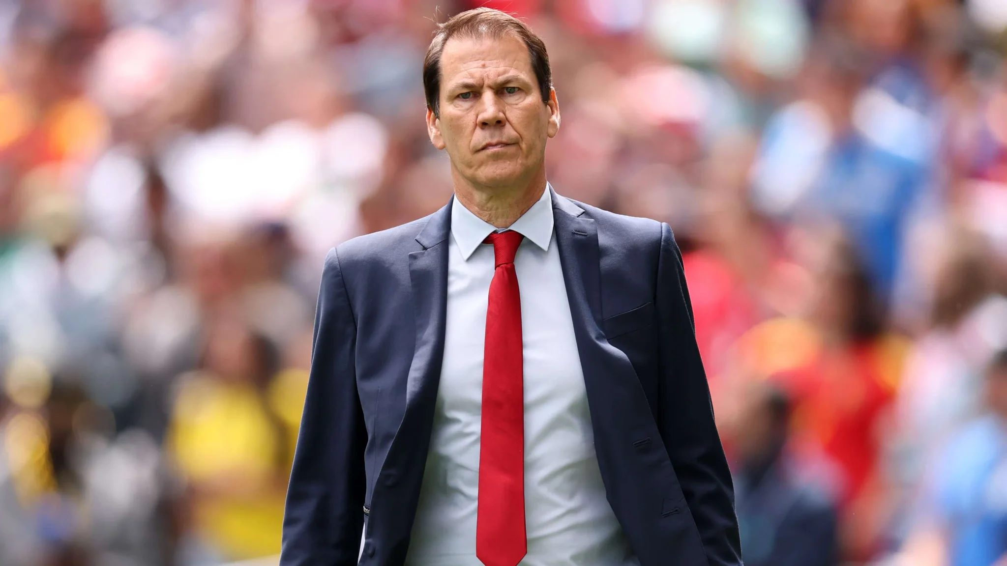 رودي غارسيا مدرب منتخب بلجيكا يرتدي بدلة رسمية وربطة عنق حمراء خلال مباراة كرة قدم حاسمة ضد السنغال.
