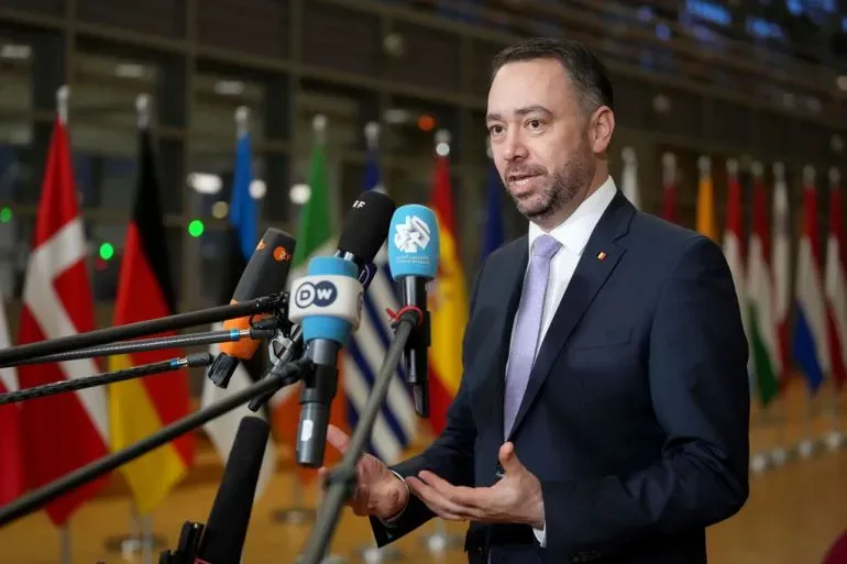 وزير الخارجية البلجيكي مكسيم بريفو يتحدث أمام ميكروفونات، مع أعلام دول خلفه، مشيرًا إلى اعتراف بلجيكا بفلسطين في الأمم المتحدة.