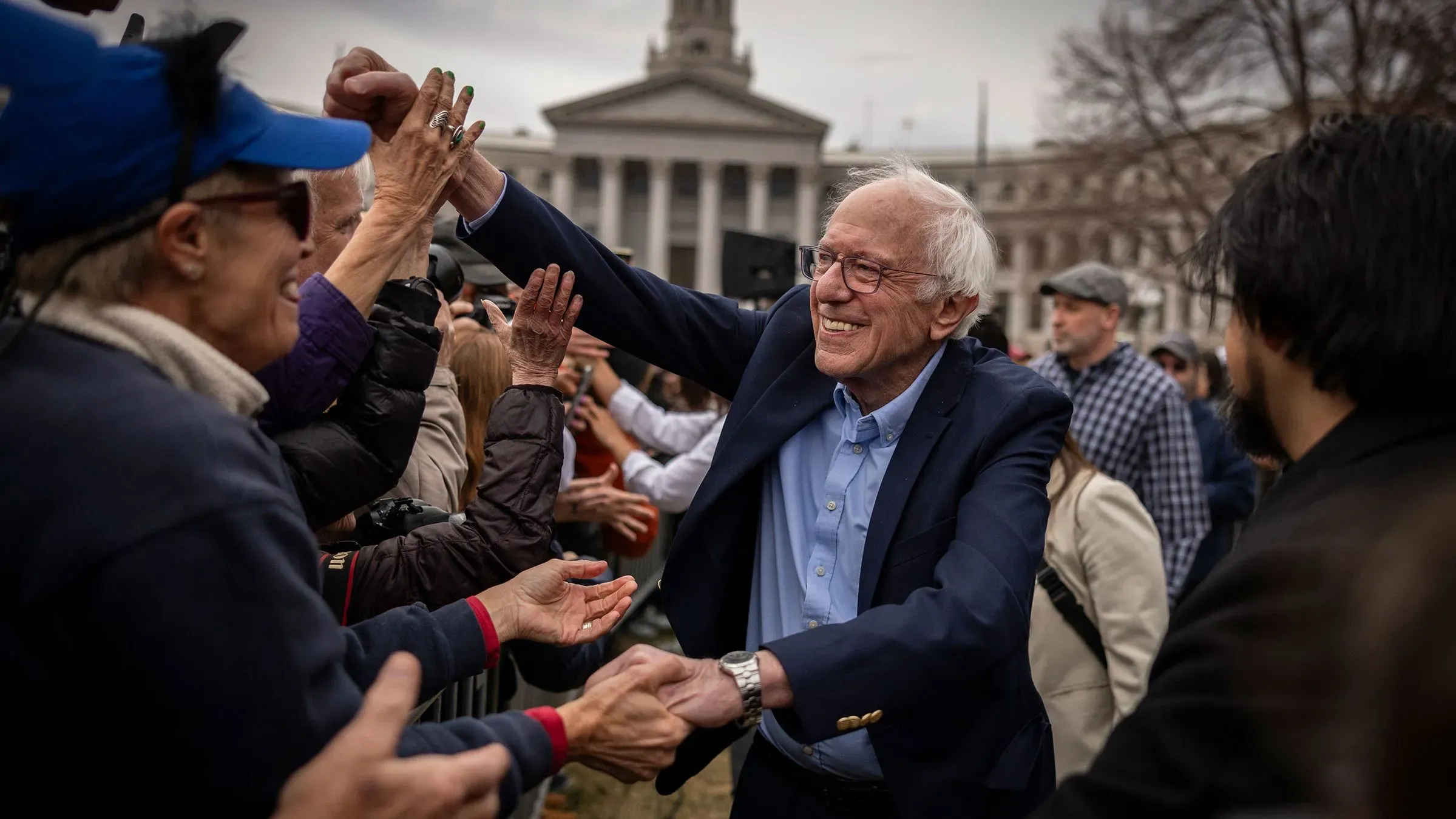 بيرني ساندرز يتفاعل مع مؤيديه في تجمع سياسي، معبراً عن دعمه للحركة التقدمية ومناهضته لإدارة ترامب.