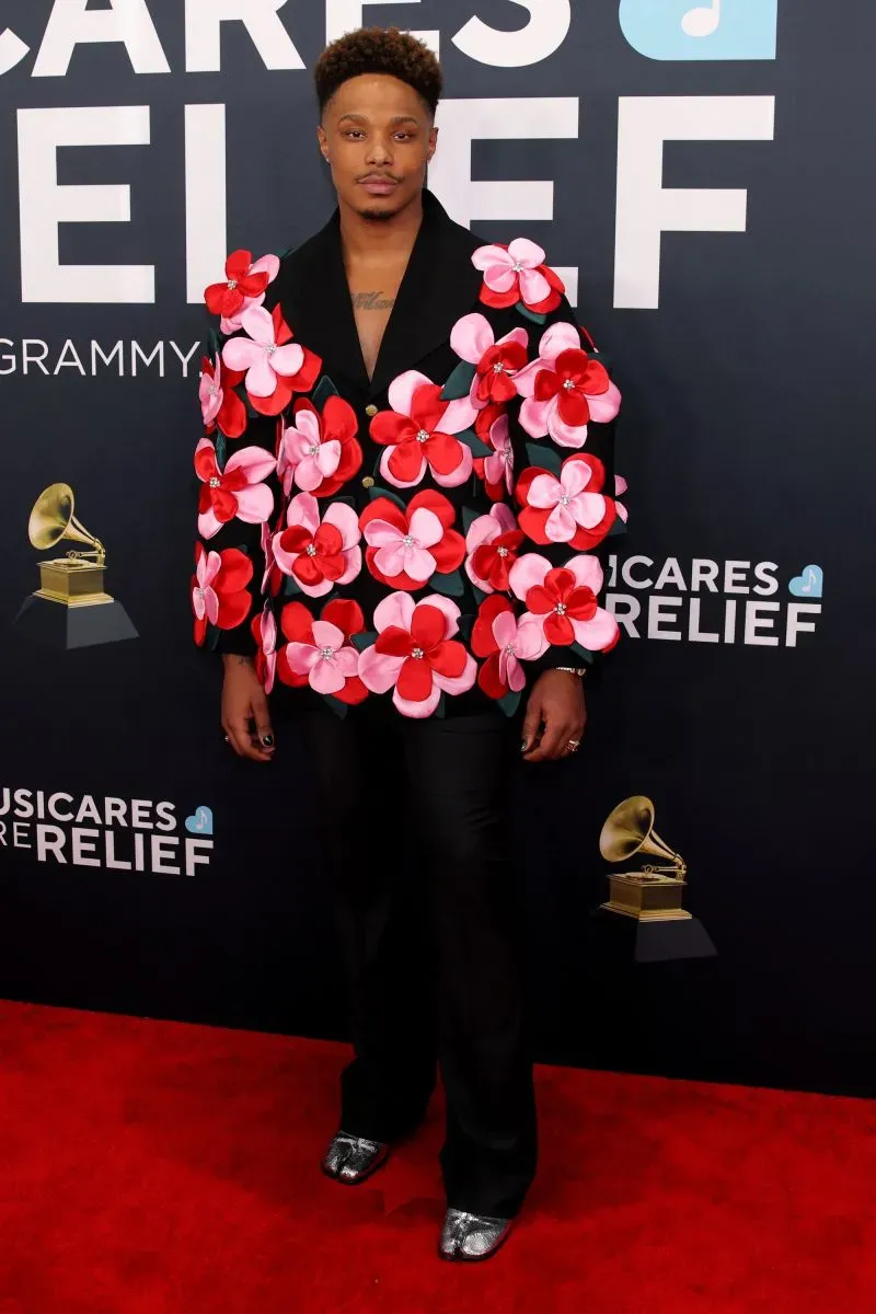 رجل يرتدي سترة مزينة بأزهار وردية وحمراء، يقف على السجادة الحمراء لحفل توزيع جوائز غرامي في لوس أنجلوس.