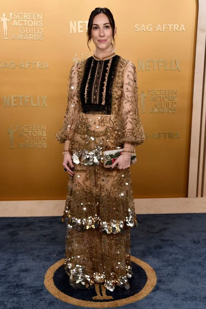 إطلالة مميزة لنجمة ترتدي فستانًا مزينًا بالخرز والذهبي، في حفل توزيع جوائز نقابة ممثلي الشاشة، مع خلفية تحمل شعار "نتفليكس".