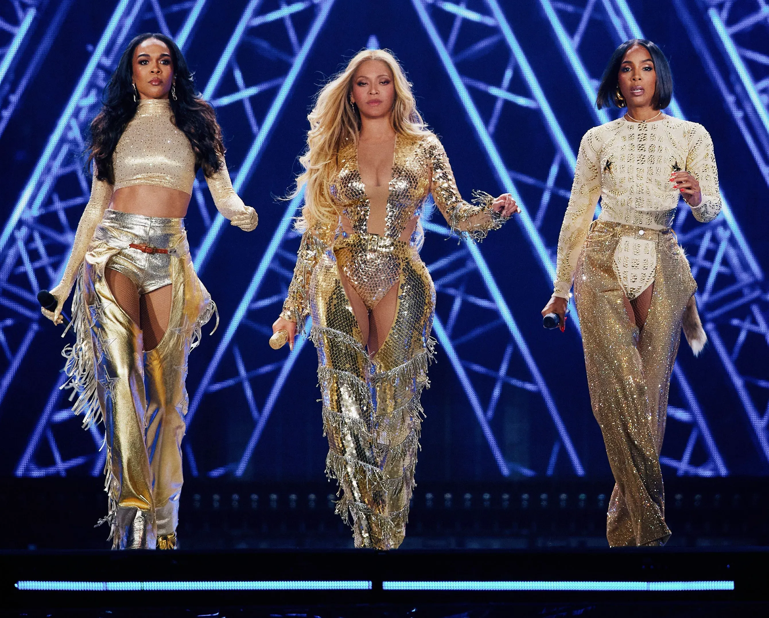 ثلاث فنانات يرتدين أزياء ذهبية، بيونسيه وميشيل ويليامز وكيلي رولاند، يتألقن على المسرح خلال عرضهن في لاس فيغاس.