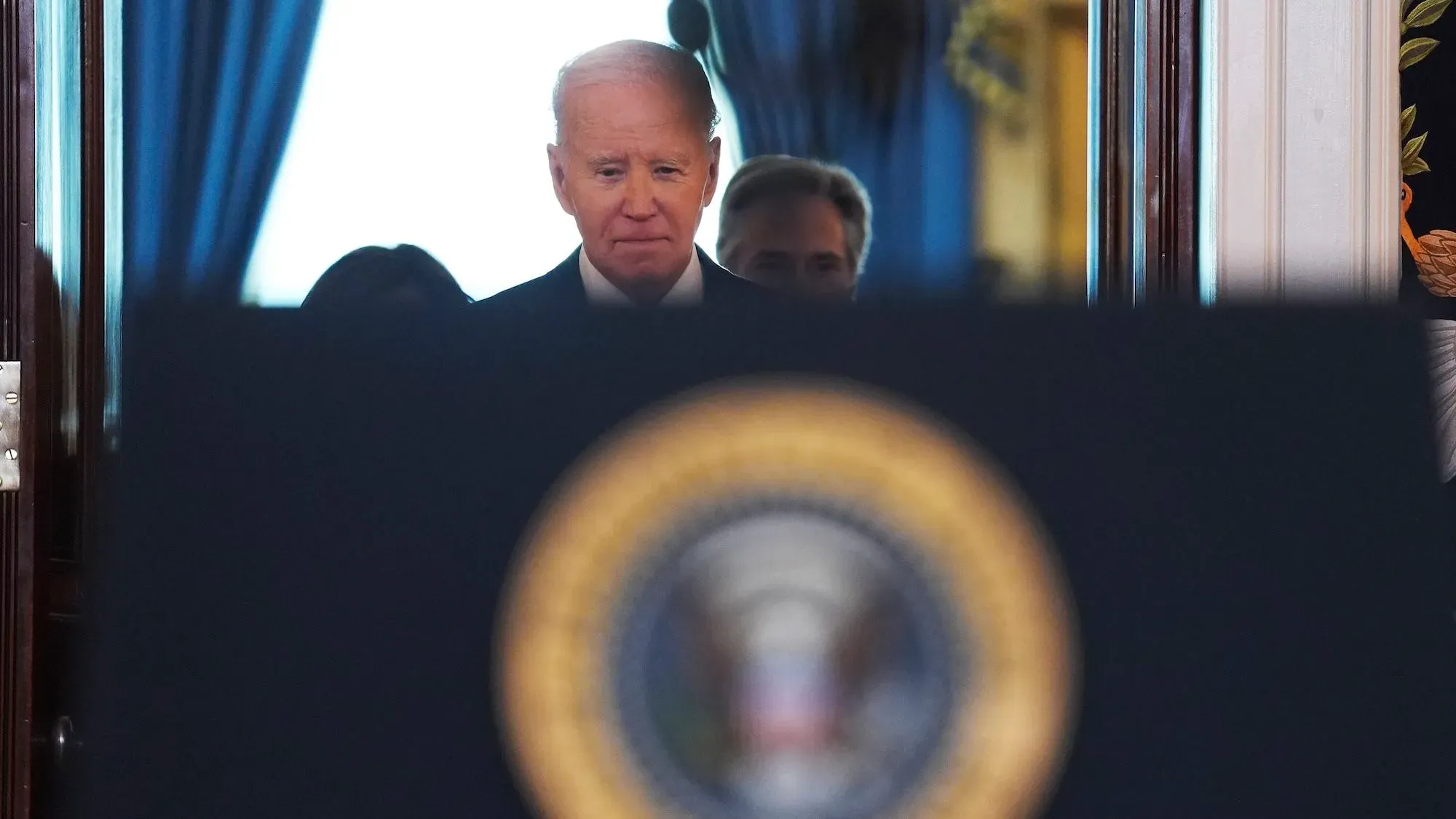 الرئيس جو بايدن يقف خلف منصة تحمل شعار الرئاسة، مع تعبير جاد، خلال إعلان عن تعزيز الدفاعات الإلكترونية الأمريكية.