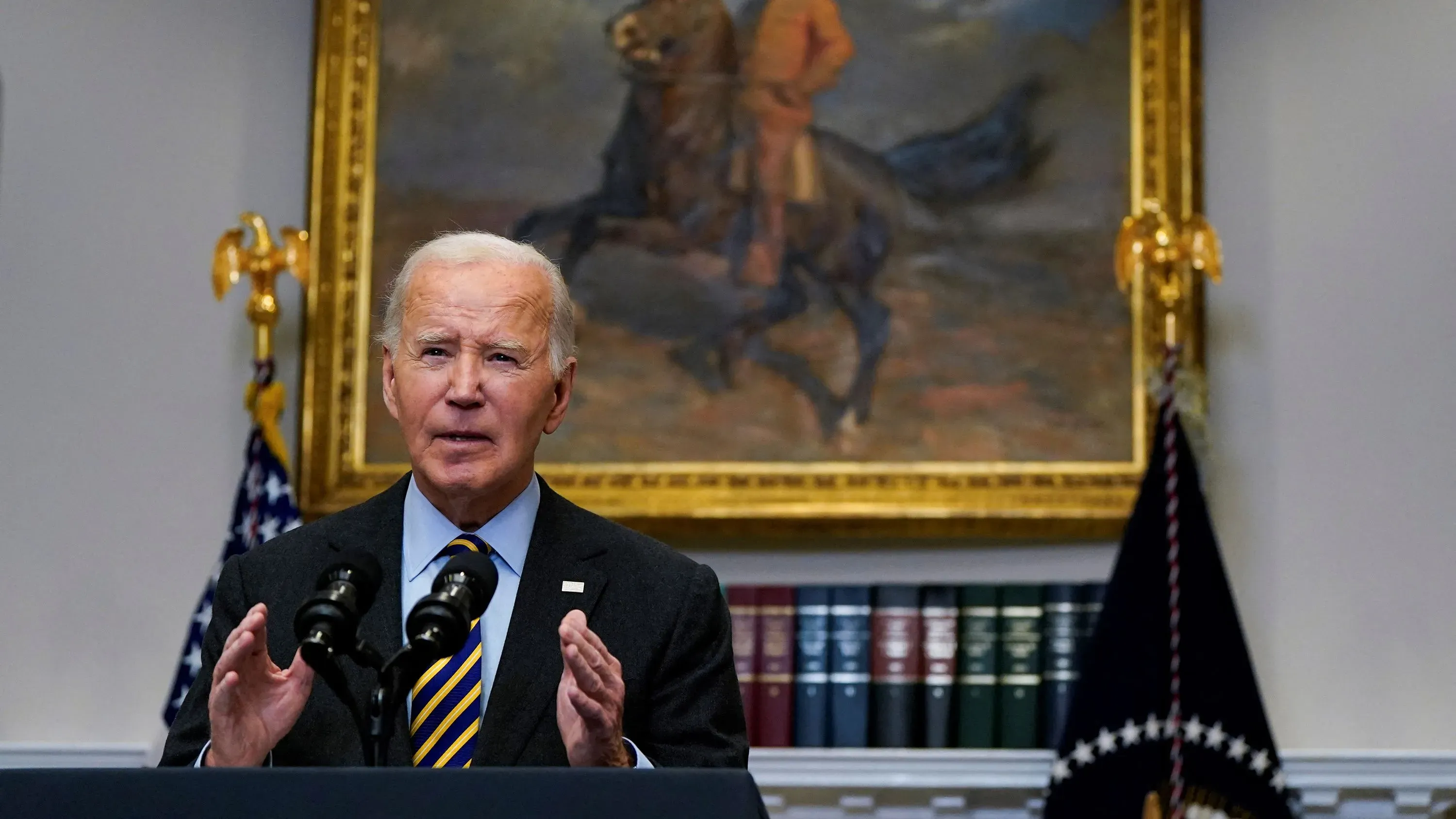 تحدث بايدن خلال مؤتمر صحفي، مشيرًا إلى المكاسب الاقتصادية المهمة في فترته الرئاسية، في خلفية تحمل لوحة تاريخية.