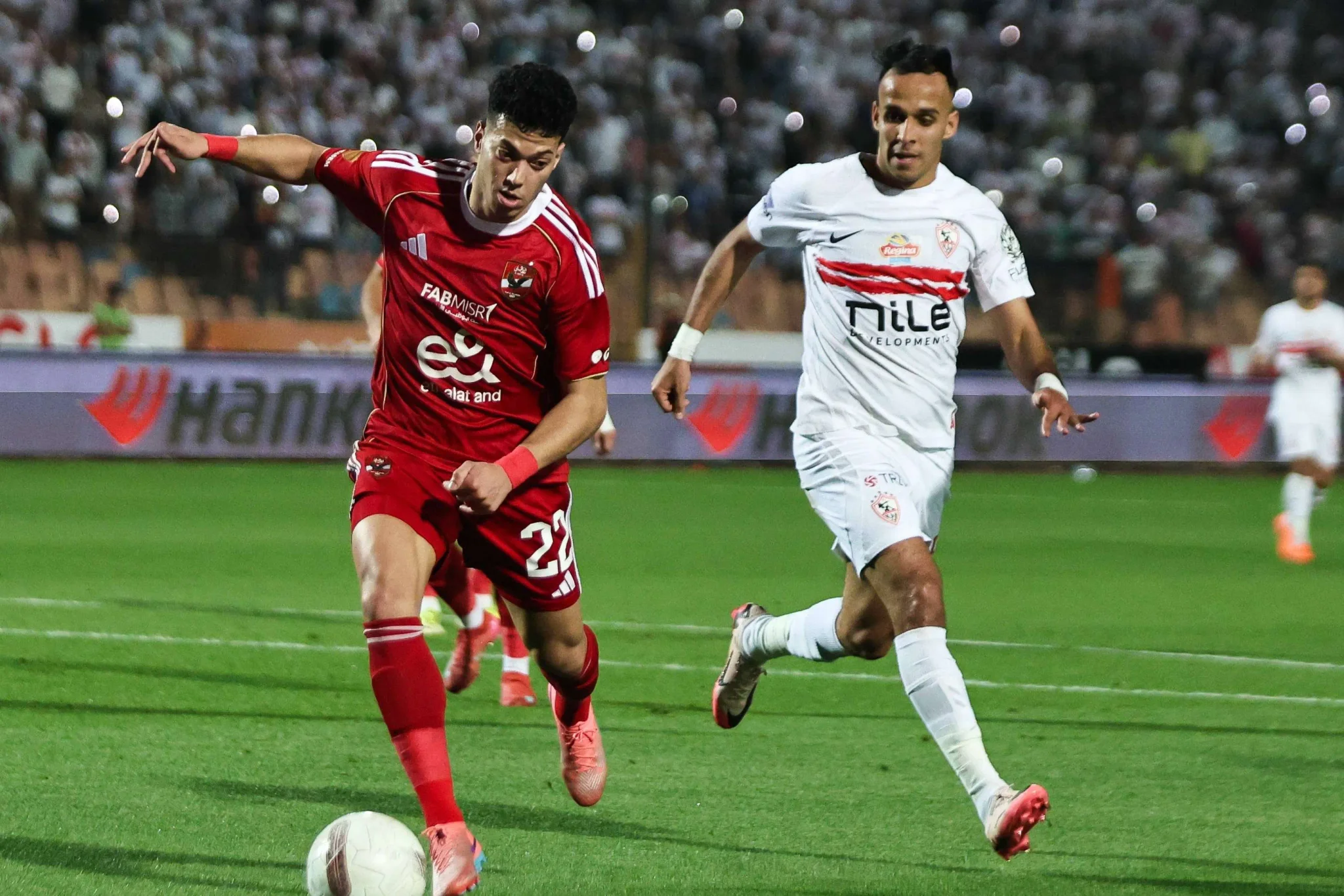 لاعبو الأهلي والزمالك يتنافسان على الكرة خلال مباراة حماسية في الدوري المصري الممتاز، تعكس التنافس الكروي بين الفريقين الكبيرين.