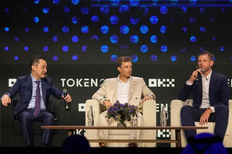 رائد الأعمال في العملات الرقمية جاستن صن يتحدث في مؤتمر، محاطاً بشخصين آخرين، وسط خلفية تكنولوجية ملونة، في سياق دعوى قضائية ضد World Liberty Financial.