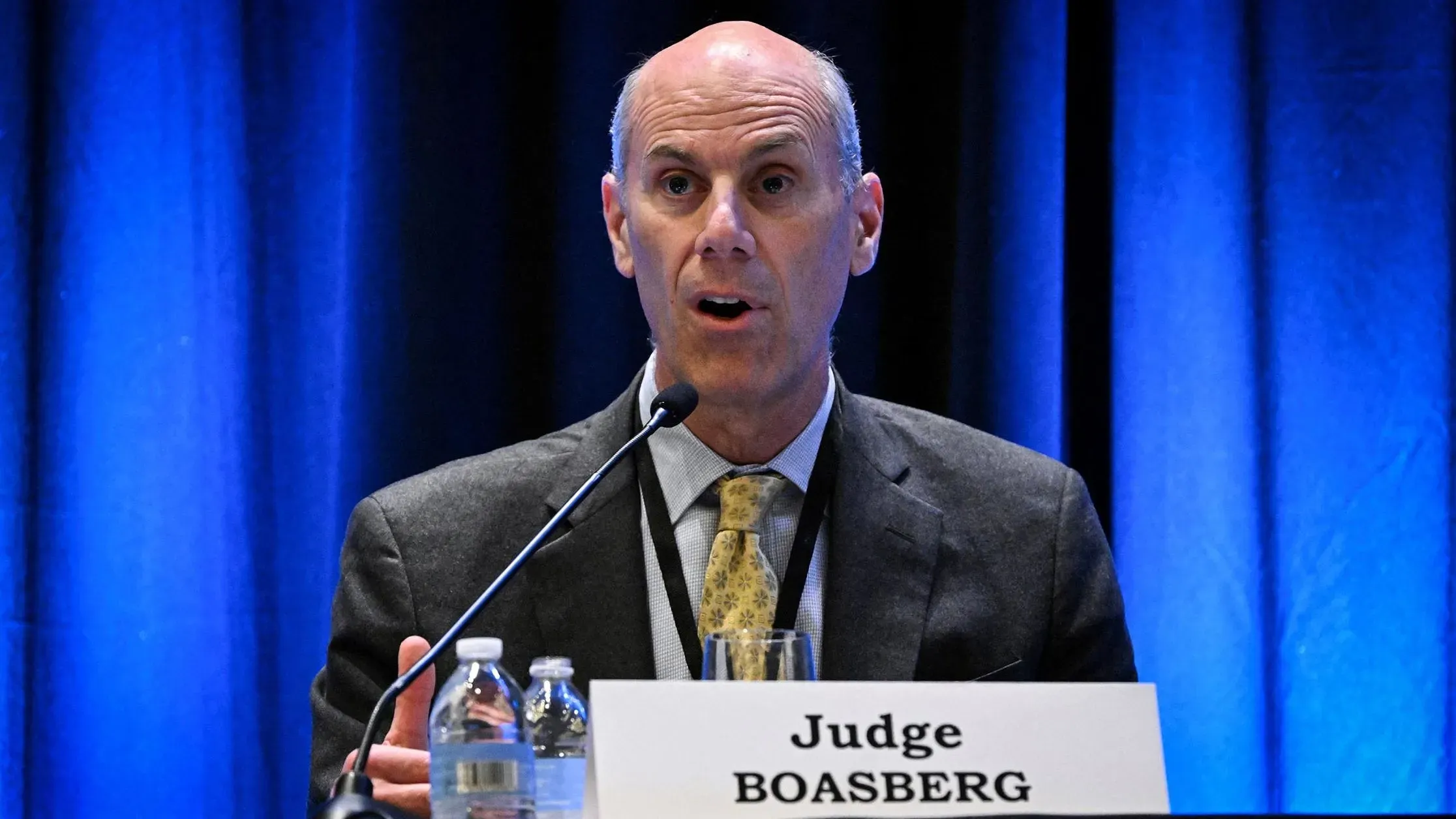 القاضي جيمس بواسبرغ يتحدث خلال مؤتمر، مع إضاءة زرقاء خلفه، حيث يناقش قضية الازدراء الجنائي المتعلقة بإدارة ترامب.