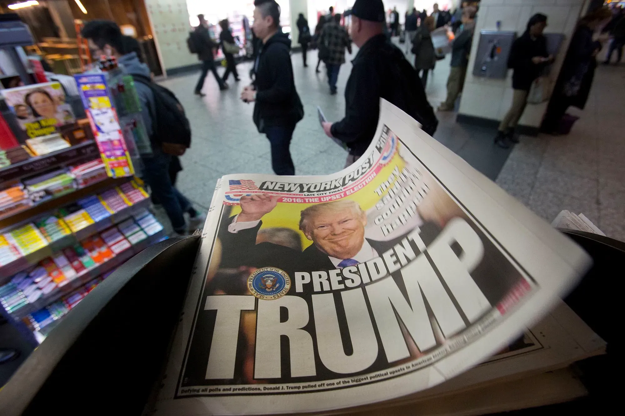 غلاف صحيفة نيويورك بوست يظهر عنوان "الرئيس ترامب" مع صورة له، في مشهد مزدحم لأشخاص يتجولون في محطة.