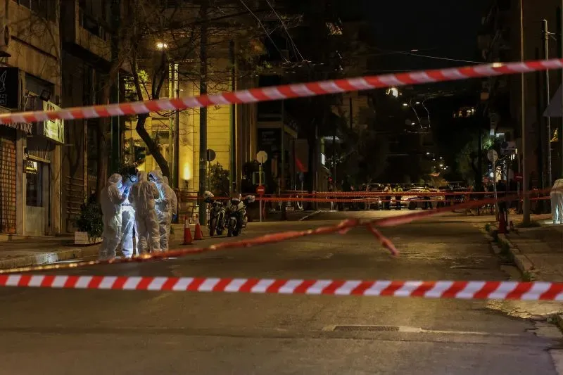 منطقة محاطة بشريط أمني بعد انفجار خارج مكاتب شركة هيلينيك ترين في أثينا، مع وجود عناصر من الشرطة في الموقع.