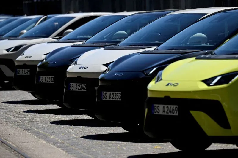 صف من السيارات الكهربائية بألوان متنوعة، بما في ذلك الأسود والأبيض والأصفر، يعكس التنافس بين الاتحاد الأوروبي والصين في سوق السيارات.