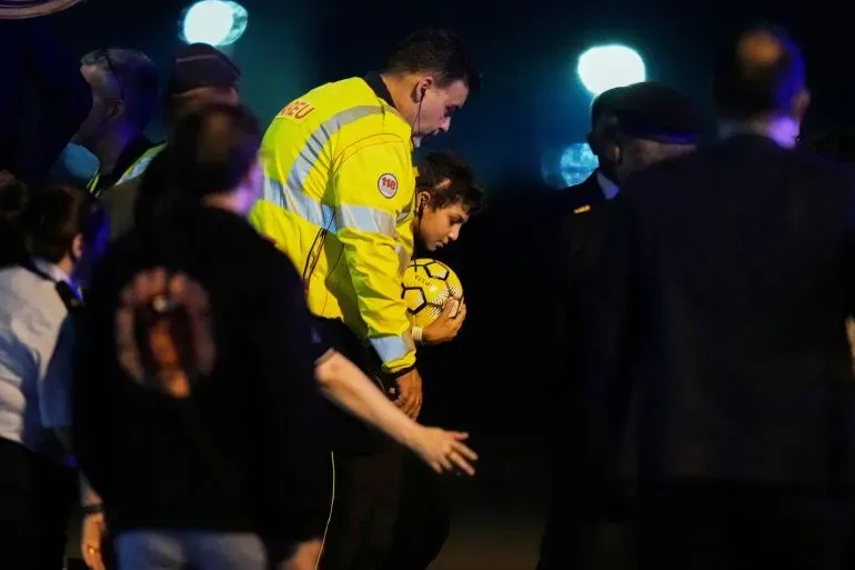 وصول طفل فلسطيني يحمل كرة قدم، برفقة مسؤولين، إلى مطار ميلانو لتلقي العلاج بعد إصابته في غارة إسرائيلية.