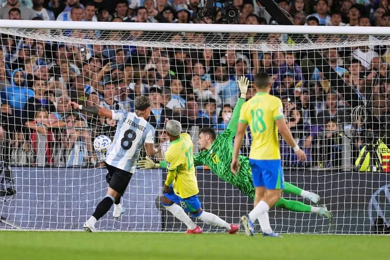 إنزو فرنانديز يسجل هدفاً للأرجنتين في مرمى البرازيل خلال مباراة تصفيات كأس العالم 2026، حيث يظهر حارس البرازيل في محاولة للتصدي.