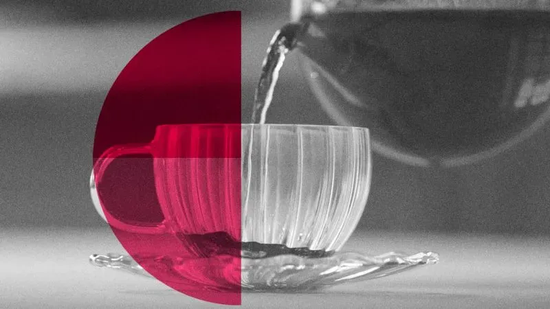 شاي يُسكب في كوب شفاف مع طبق، مع خلفية بسيطة، يسلط الضوء على فوائد تخمير الشاي في امتصاص المعادن الثقيلة.