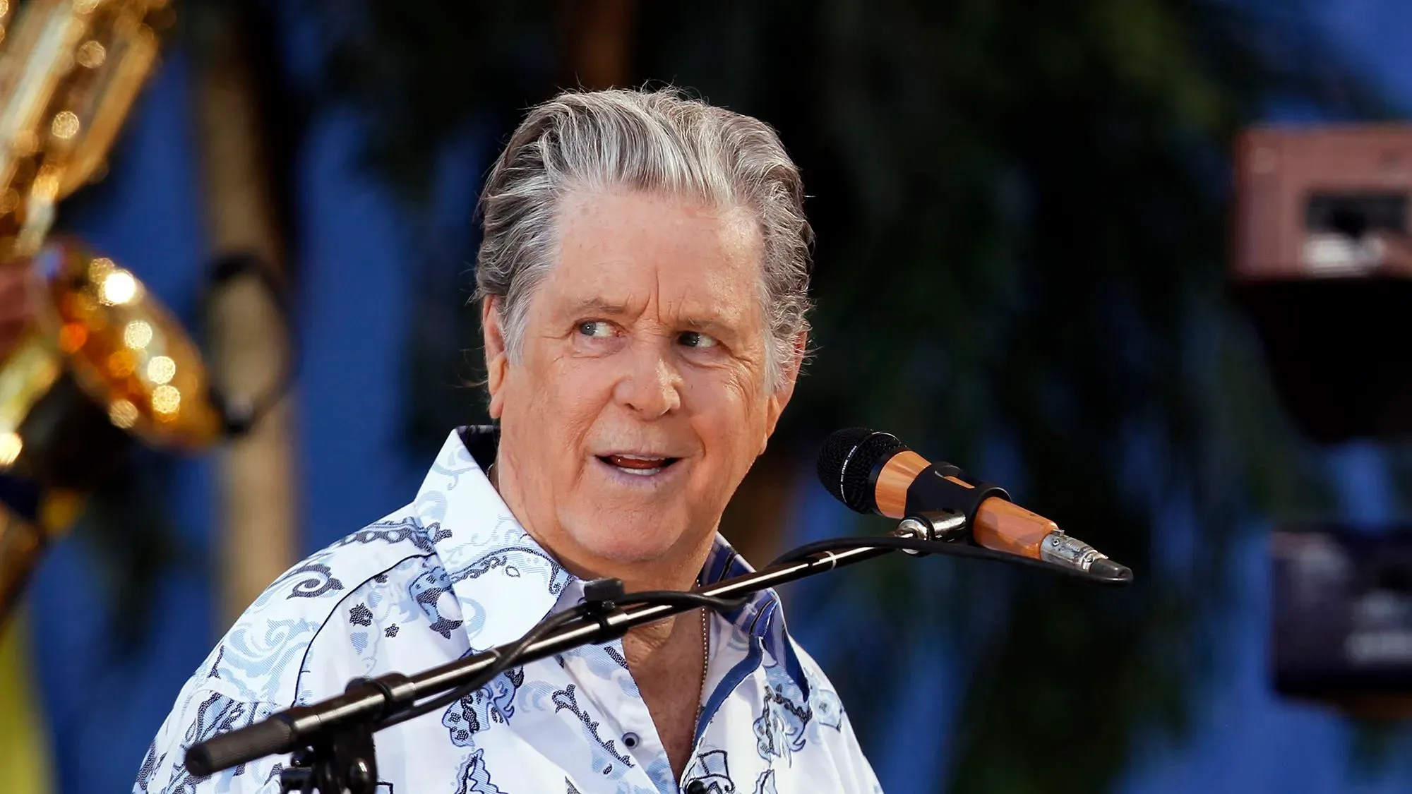 تظهر الصورة براين ويلسون، مؤسس فرقة ذا بيتش بويز، أثناء أدائه الموسيقي، مع تعبيرات وجه تعكس شغفه بالموسيقى.