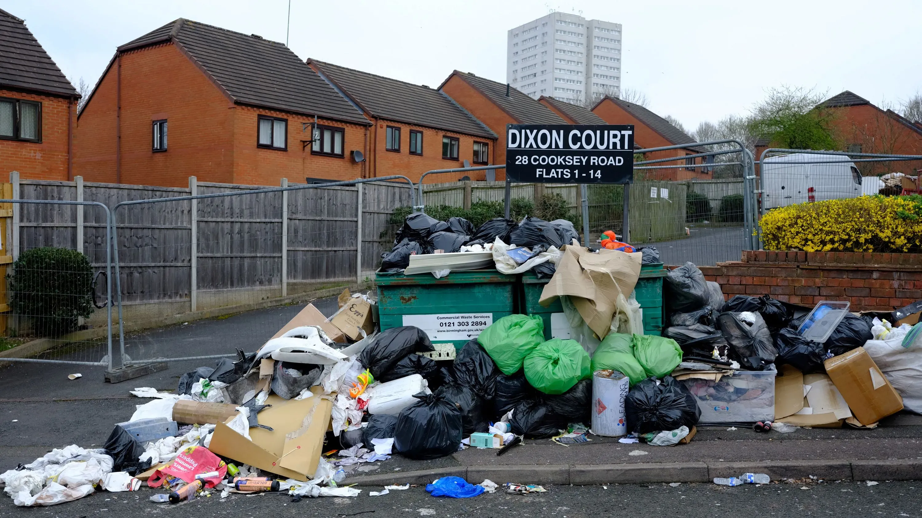 تظهر الصورة أكوامًا من القمامة المتراكمة أمام صناديق النفايات في برمنغهام، مما يعكس تأثير إضراب عمال النظافة على المدينة.