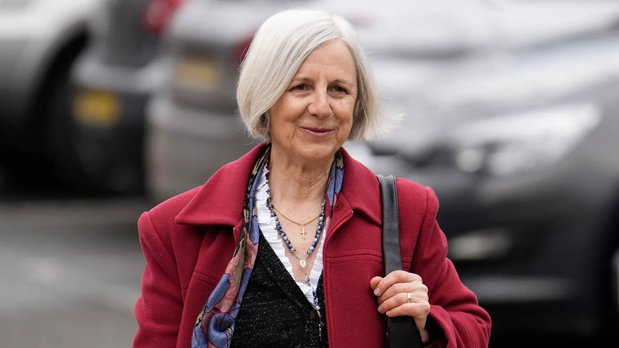 امرأة مسنّة ترتدي معطفًا أحمر، تتجه نحو عيادة إجهاض في بورنموث، تعبيرها يدل على الهدوء، في سياق قضية تتعلق بحرية التعبير.