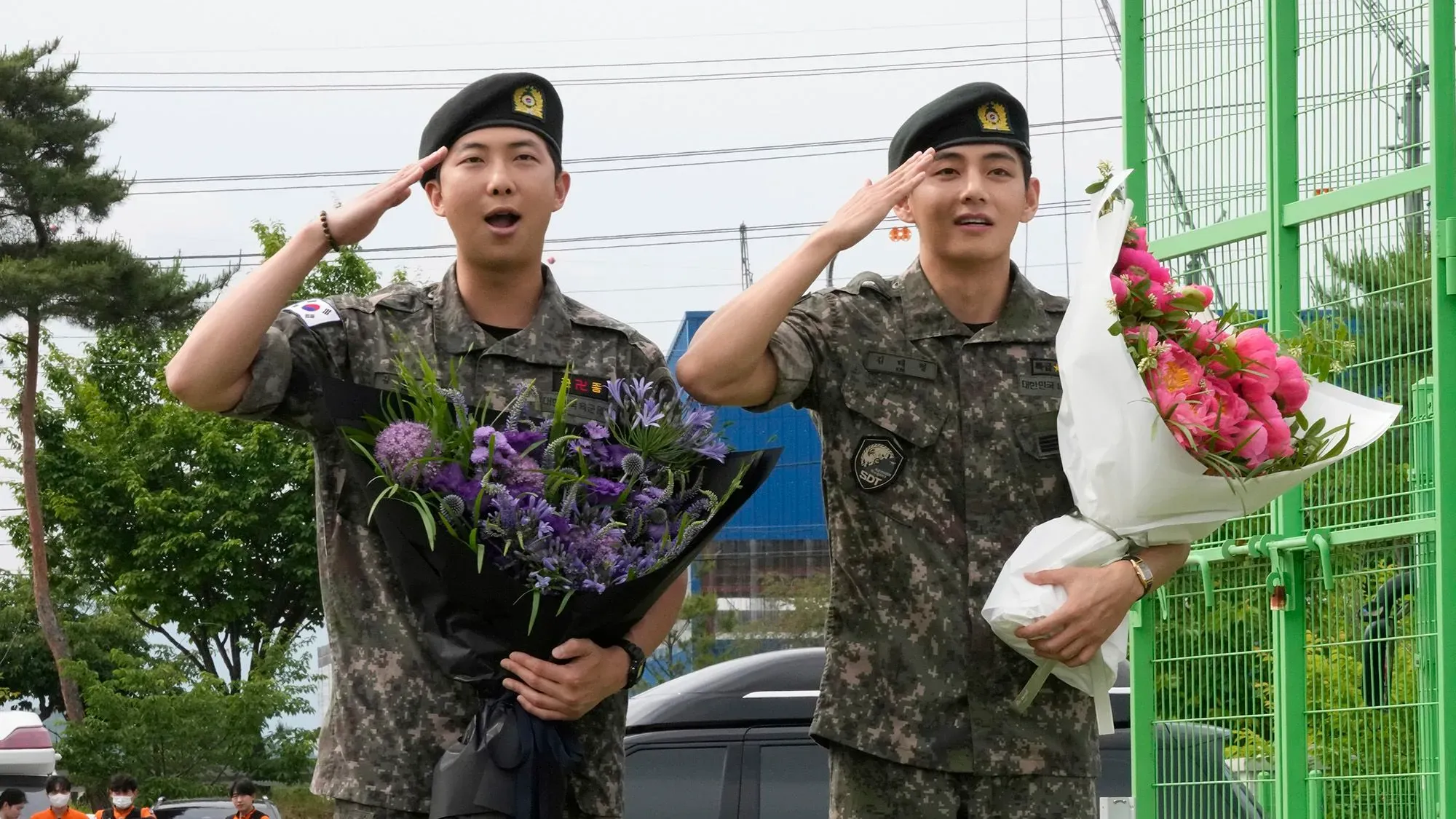يظهر RM وV من فرقة BTS في زي الجيش، يؤدون التحية العسكرية ويحملان باقات من الزهور وسط حشد من المعجبين في تشونتشون.