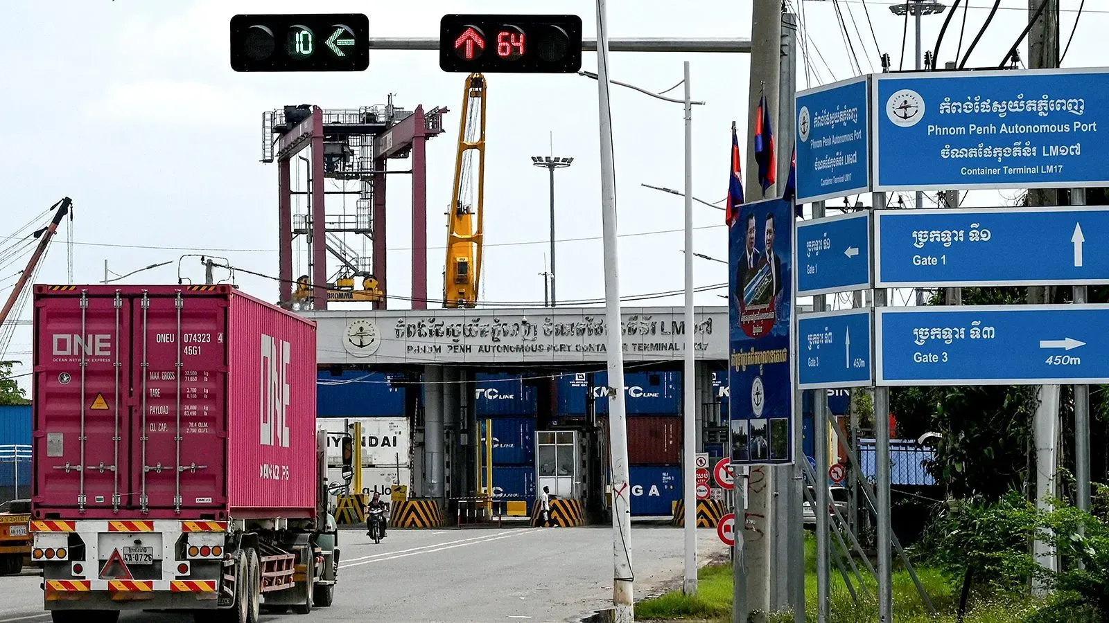 صورة لميناء بنوم بنه في كمبوديا، تُظهر شاحنة تحمل حاوية ورداءً للإشارات المرورية، في سياق التأثيرات الاقتصادية للتعريفات الجمركية الأمريكية.
