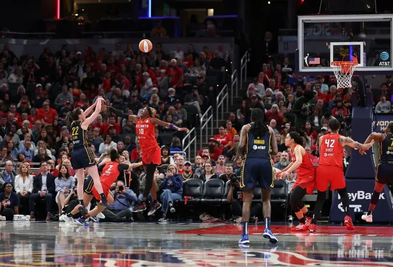 تسديدة حاسمة من لاعبة أتلانتا، مع تواجد لاعبات إنديانا في الخلفية، أثناء مباراة مثيرة في دوري كرة السلة الأمريكي للمحترفين.