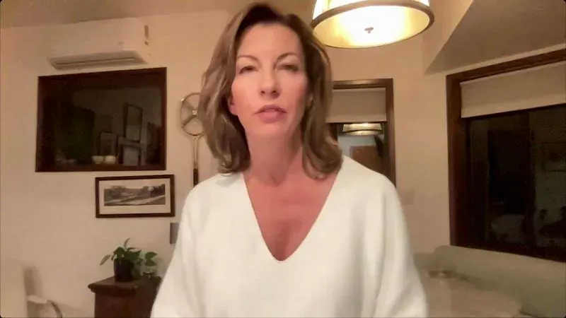 امرأة تتحدث في غرفة مضاءة بشكل خافت، تعبر عن مشاعرها حول الحرائق التي دمرت منازل في كاليفورنيا.