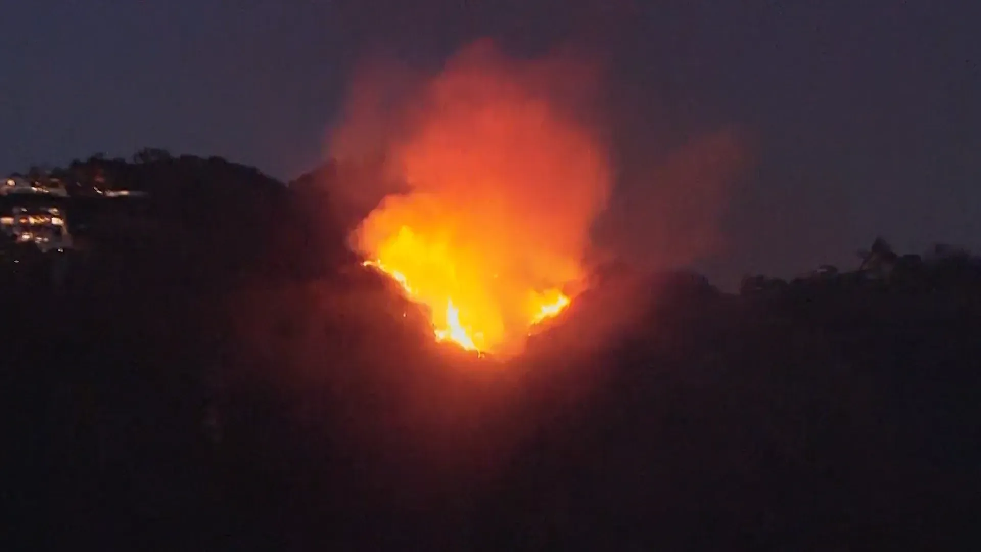 لهب كبير يشتعل على قمة تل في مقاطعة لوس أنجلوس، مع تصاعد الدخان الكثيف في السماء، مما يعكس خطر حرائق الغابات المتزايد.