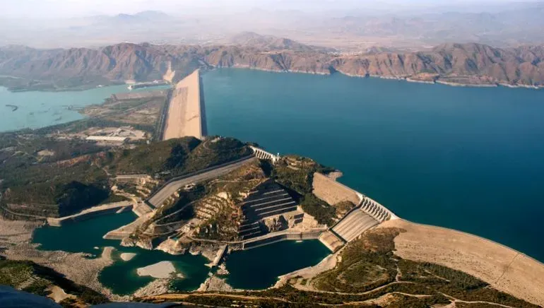 مشهد جوي لسد كبير يسيطر على المياه، مع مناظر طبيعية جبلية وسهول، يعكس التوترات المائية بين الهند وباكستان.