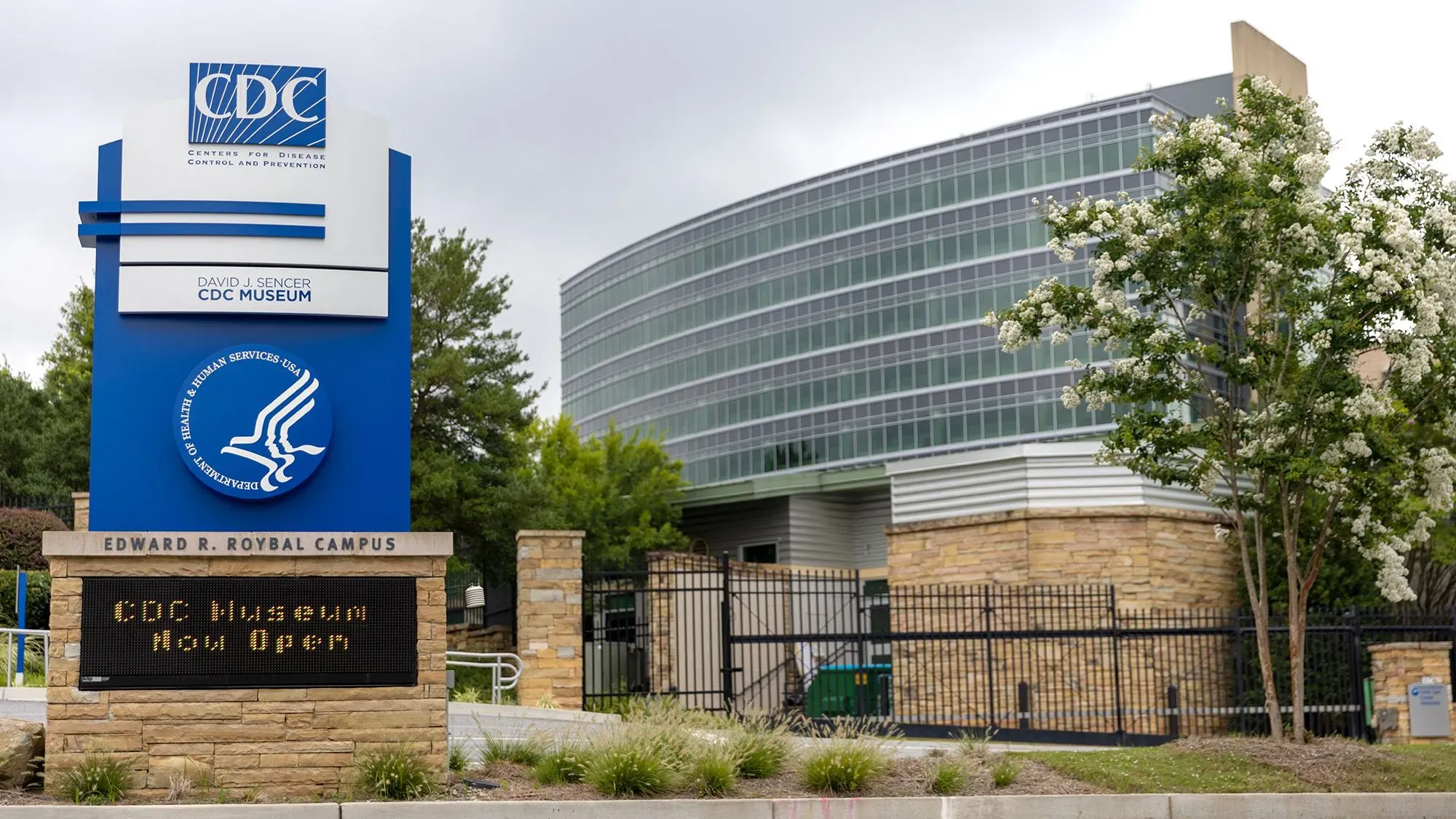 مبنى مركز السيطرة على الأمراض والوقاية منها (CDC) في أتلانتا، مع لافتة تشير إلى افتتاح المتحف الجديد، محاط بأشجار.