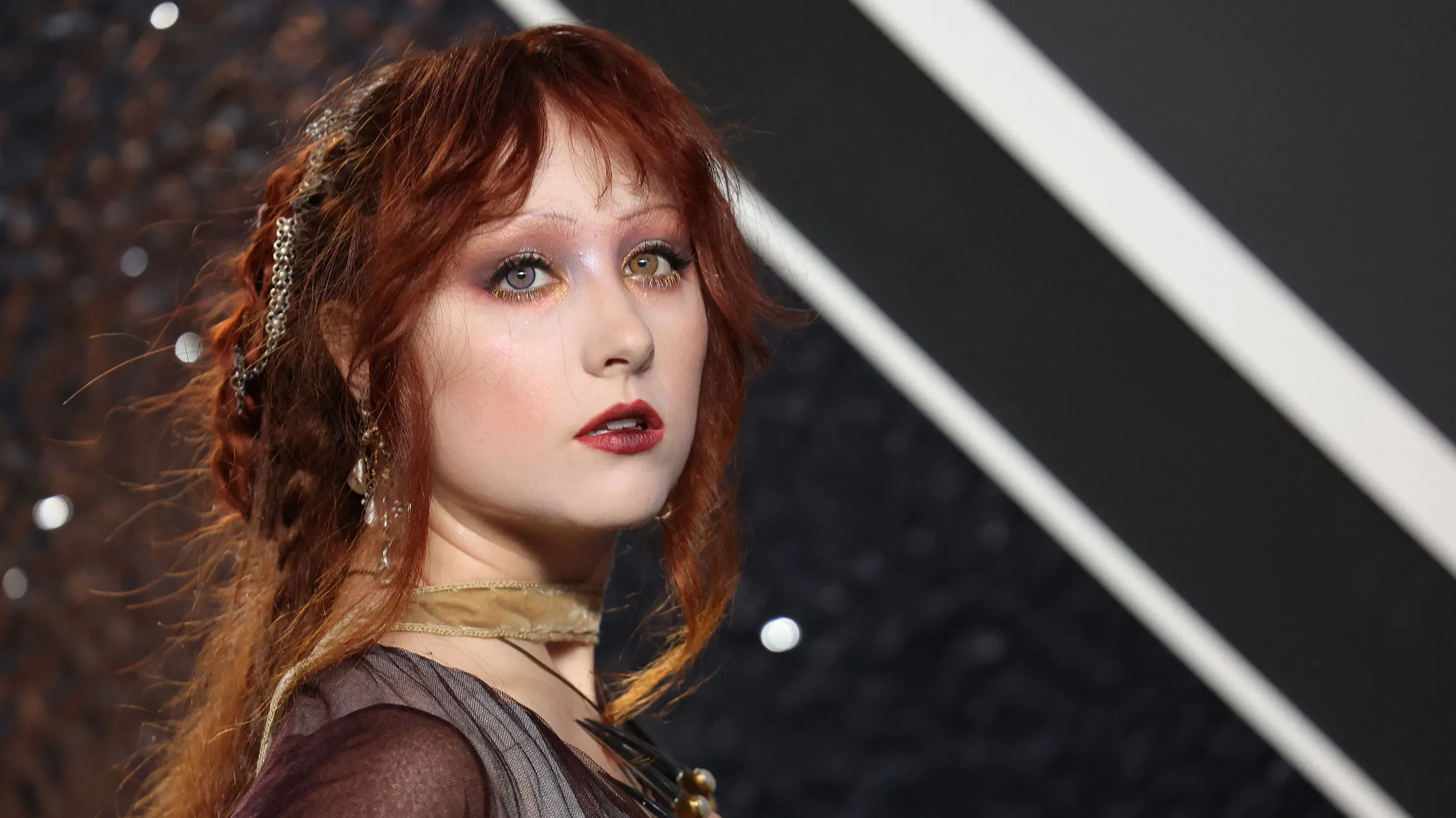 تظهر المغنية تشابيل رون في الفعالية مع تسريحة شعر مميزة وماكياج جريء، مع خلفية تعكس أجواء الحفل.