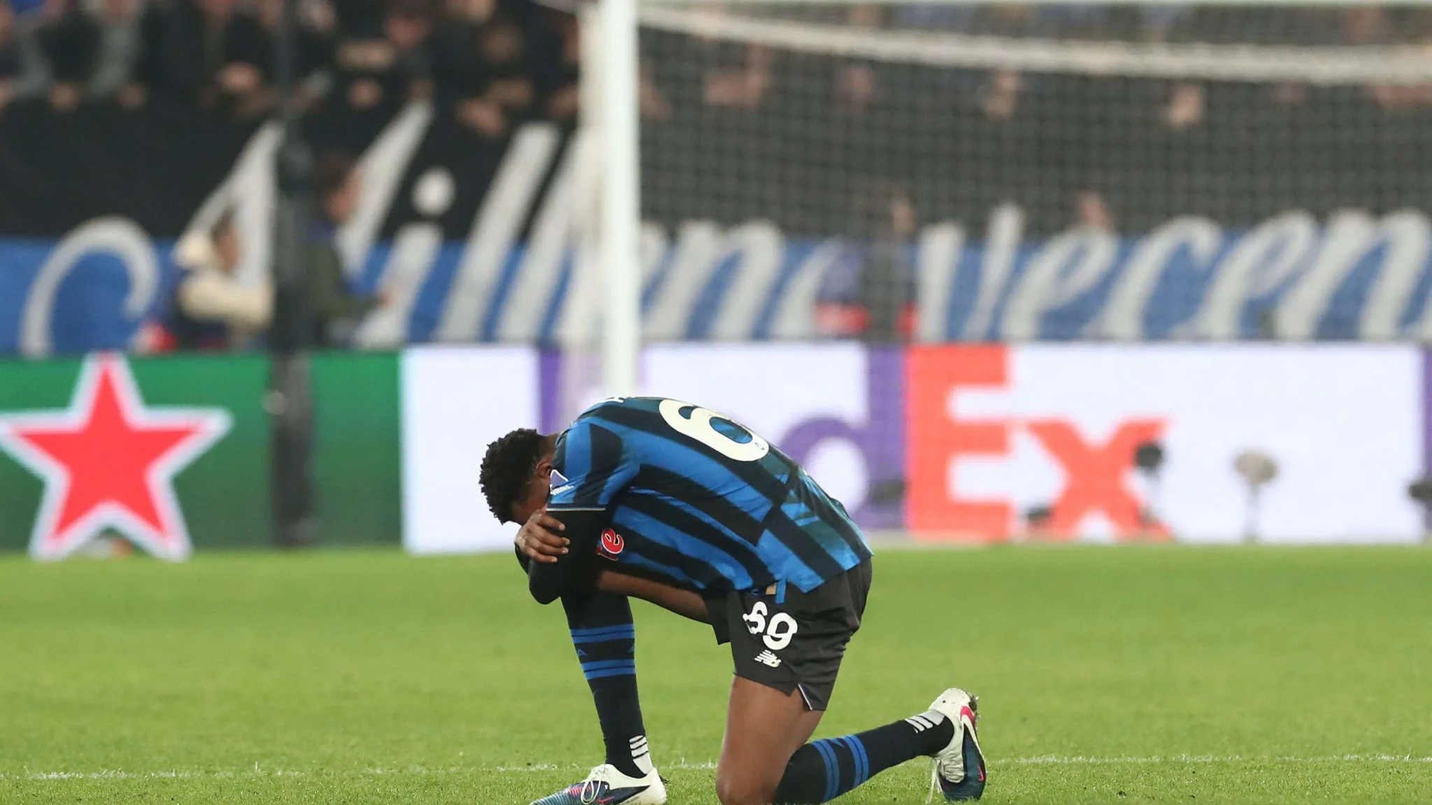 لاعب أهانور يرتدي زي أتالانتا الأزرق والأسود يركع على أرض الملعب خلال مباراة في الدوري الإيطالي، مع خلفية لشبكات الإعلانات.