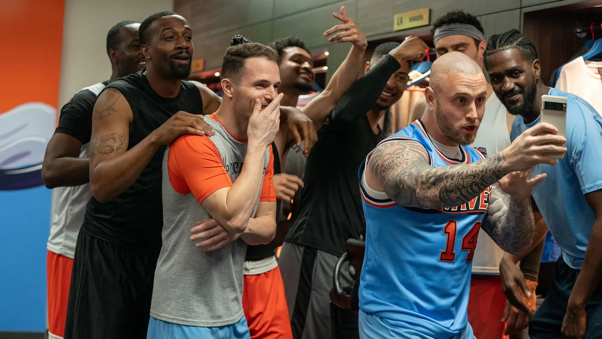 مجموعة من اللاعبين في غرفة تبديل الملابس، يظهرون في لحظة مرحة حيث يقوم أحدهم بالتقاط سيلفي مع زملائه، في إطار مسلسل "Running Point".