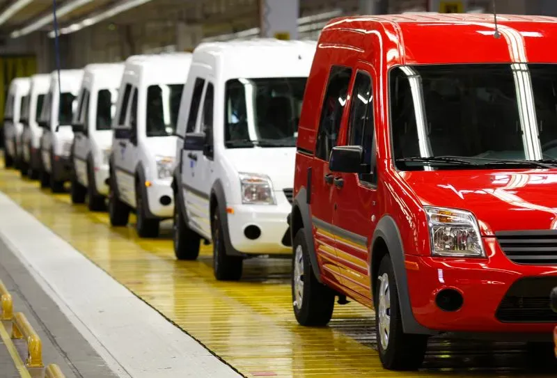 شاحنات صغيرة بألوان متعددة في خط إنتاج، تعكس تأثير التعريفات الجمركية على سوق السيارات الأمريكية.