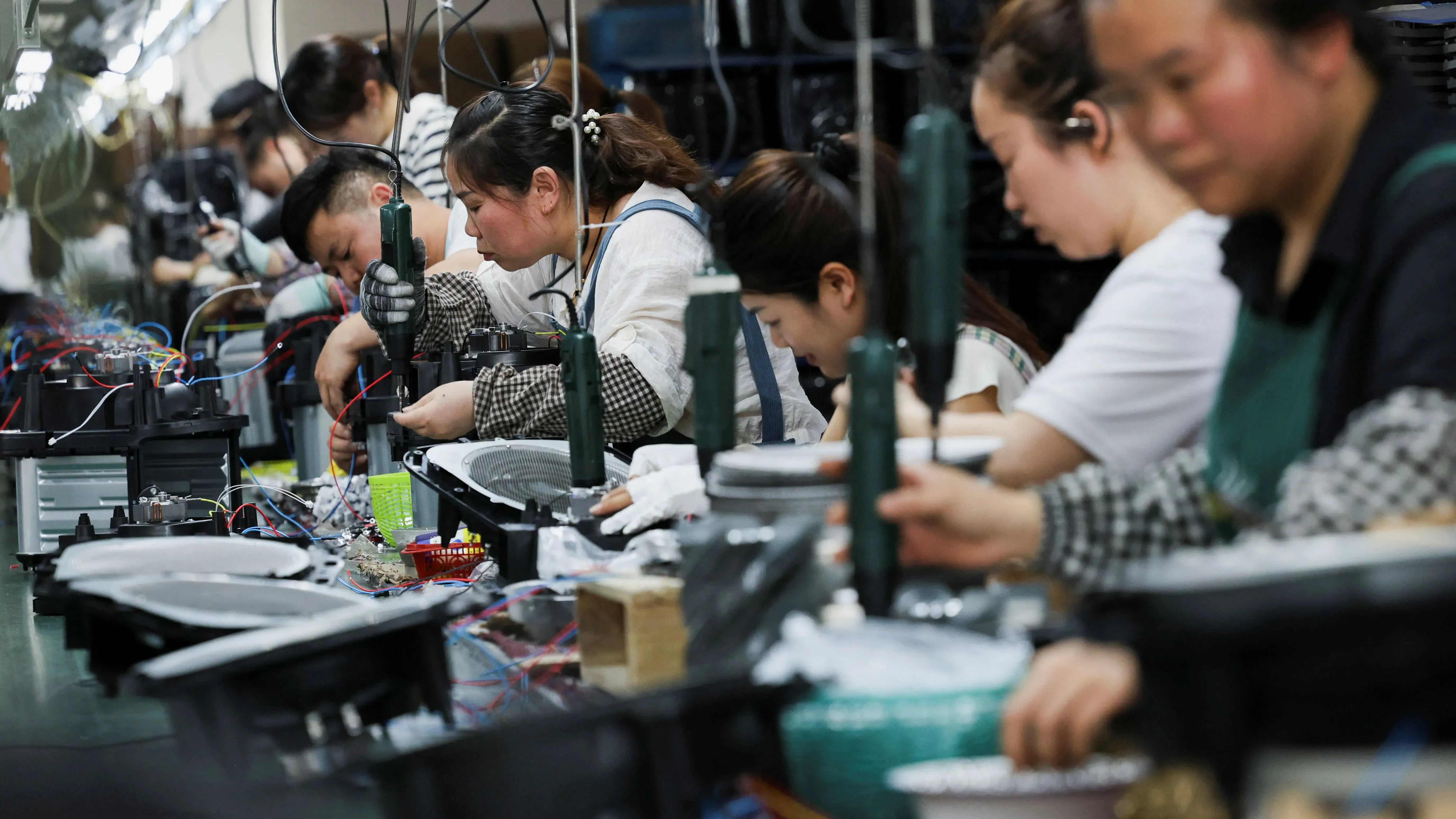 عمال في مصنع صيني يقومون بتجميع المنتجات الإلكترونية، مما يعكس زيادة الصادرات الصينية في ظل التوترات التجارية العالمية.