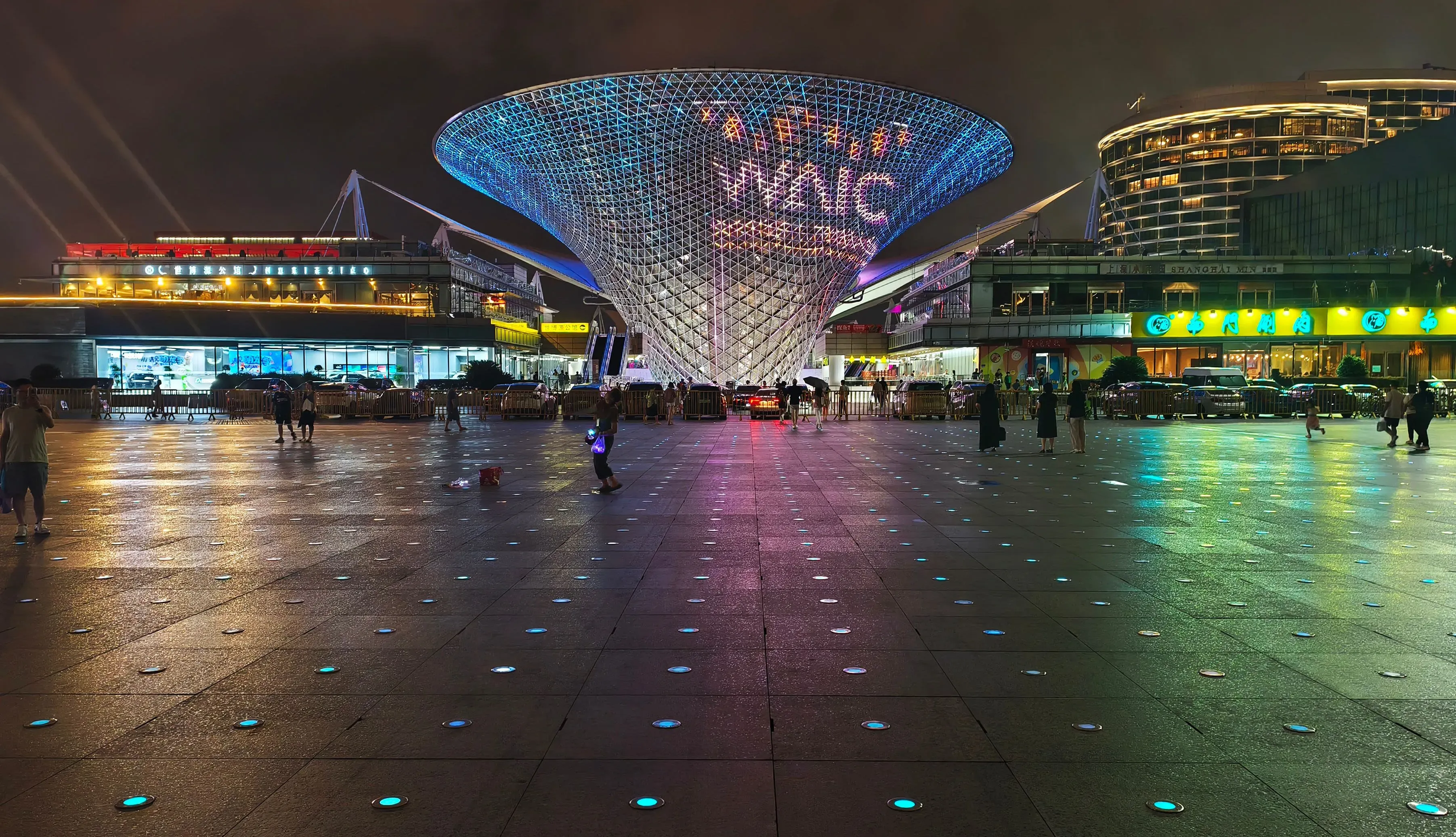 مركز عالمي للذكاء الاصطناعي في شنغهاي، يظهر بتصميم حديث وإضاءة ملونة، مع تجمعات للزوار في ساحة واسعة.