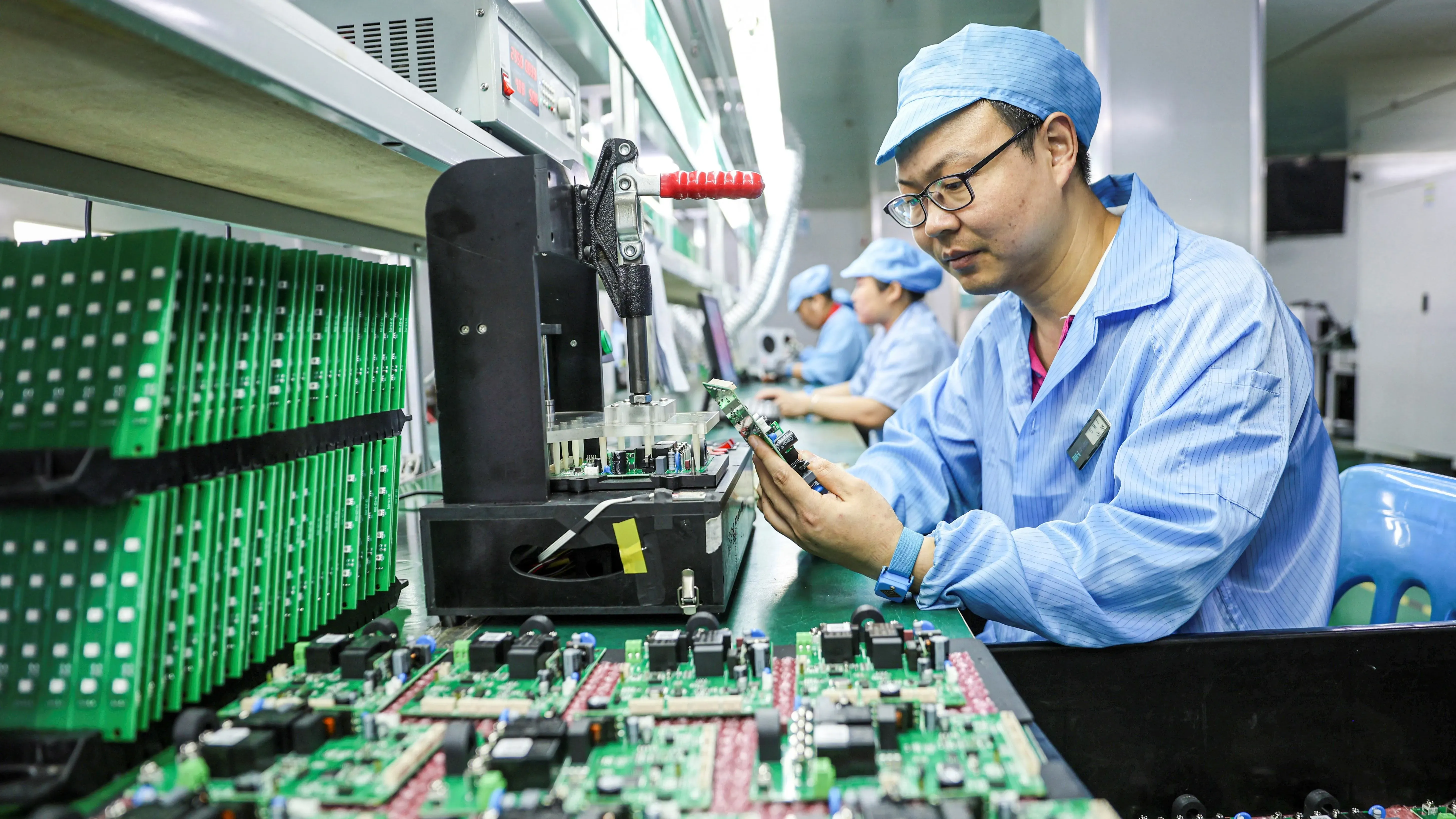 عامل يعمل في مصنع لتصنيع بطاريات السيارات الكهربائية، محاط بمكونات إلكترونية، مما يعكس هيمنة الصين في هذا القطاع.