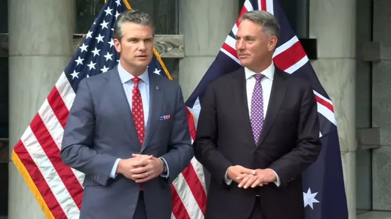 وزير الدفاع الأمريكي بيت هيغسيث مع مسؤول أسترالي، خلفهما أعلام الولايات المتحدة وأستراليا، في سياق حوار شانغريلا الأمني.