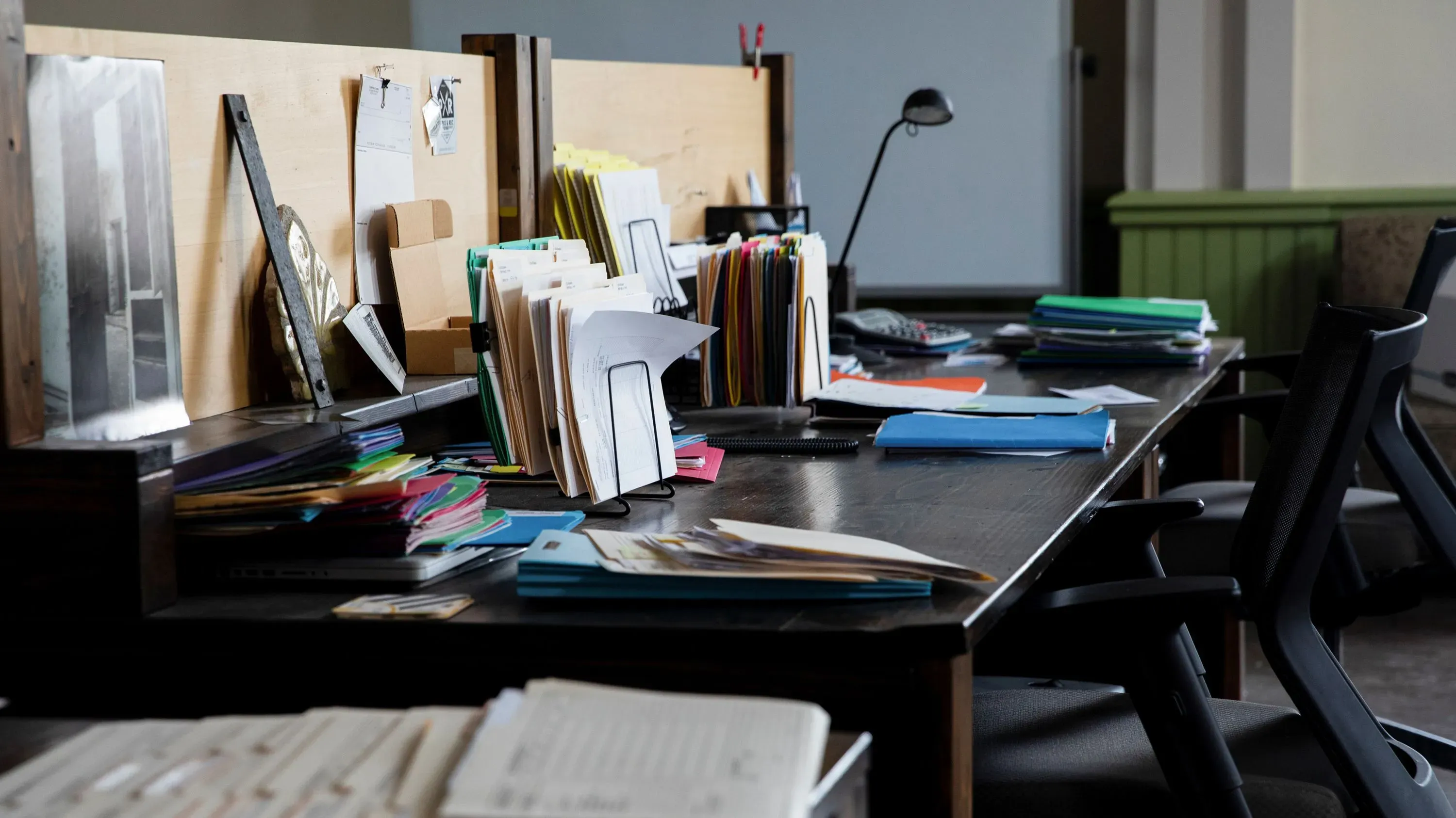 مكتب فوضوي يحتوي على ملفات ملونة وأوراق متناثرة، مما يعكس حالة من الارتباك الإداري في سياق مناقشة أصول كوفيد-19.