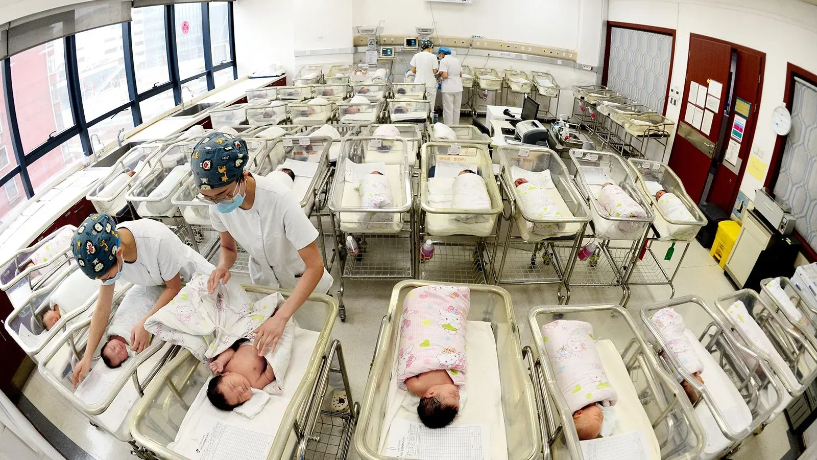 غرفة في مستشفى تحتوي على عدة أسرّة للأطفال حديثي الولادة، مع ممرضات يعتنين بهم، مما يعكس جهود تحسين رعاية الأم والطفل في الصين.
