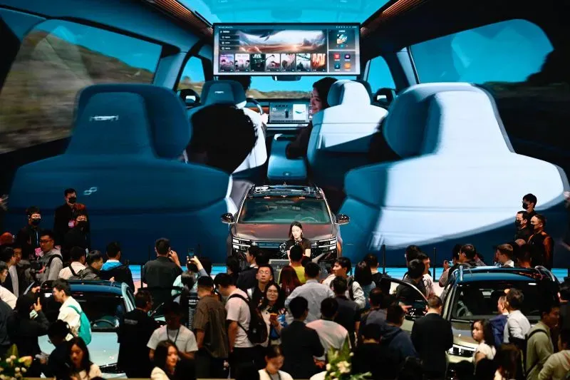 معرض شنغهاي للسيارات يبرز سيارة كهربائية حديثة وسط حشود من الزوار، مع شاشة عرض تعرض تكنولوجيا متطورة وتصميم داخلي أنيق.