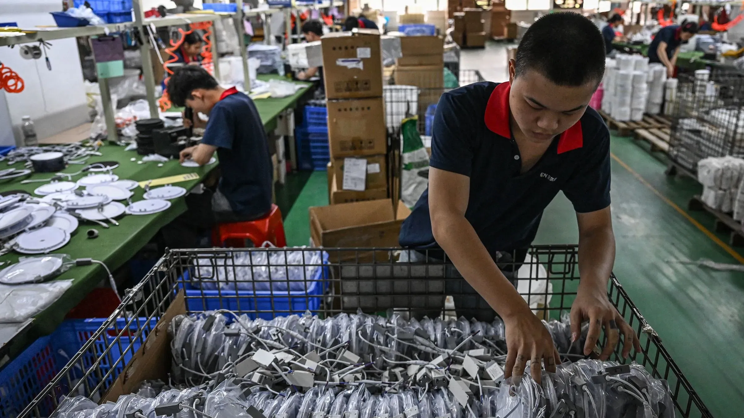 تظهر الصورة عمالًا في مصنع صيني يقومون بتجميع المنتجات، في سياق تراجع نشاط التصنيع بسبب الرسوم الجمركية الأمريكية.