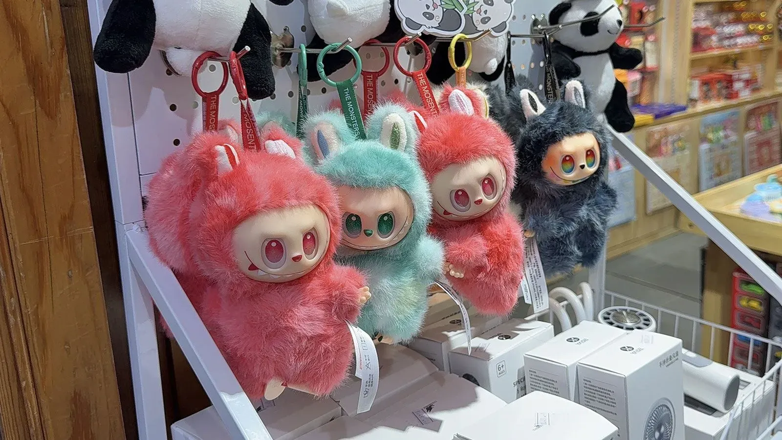 دمى "لافوفو" الملونة والمعلقة في متجر، تظهر بأشكال غريبة وجذابة، تعكس شعبية الدمى المقلدة في الأسواق الصينية.