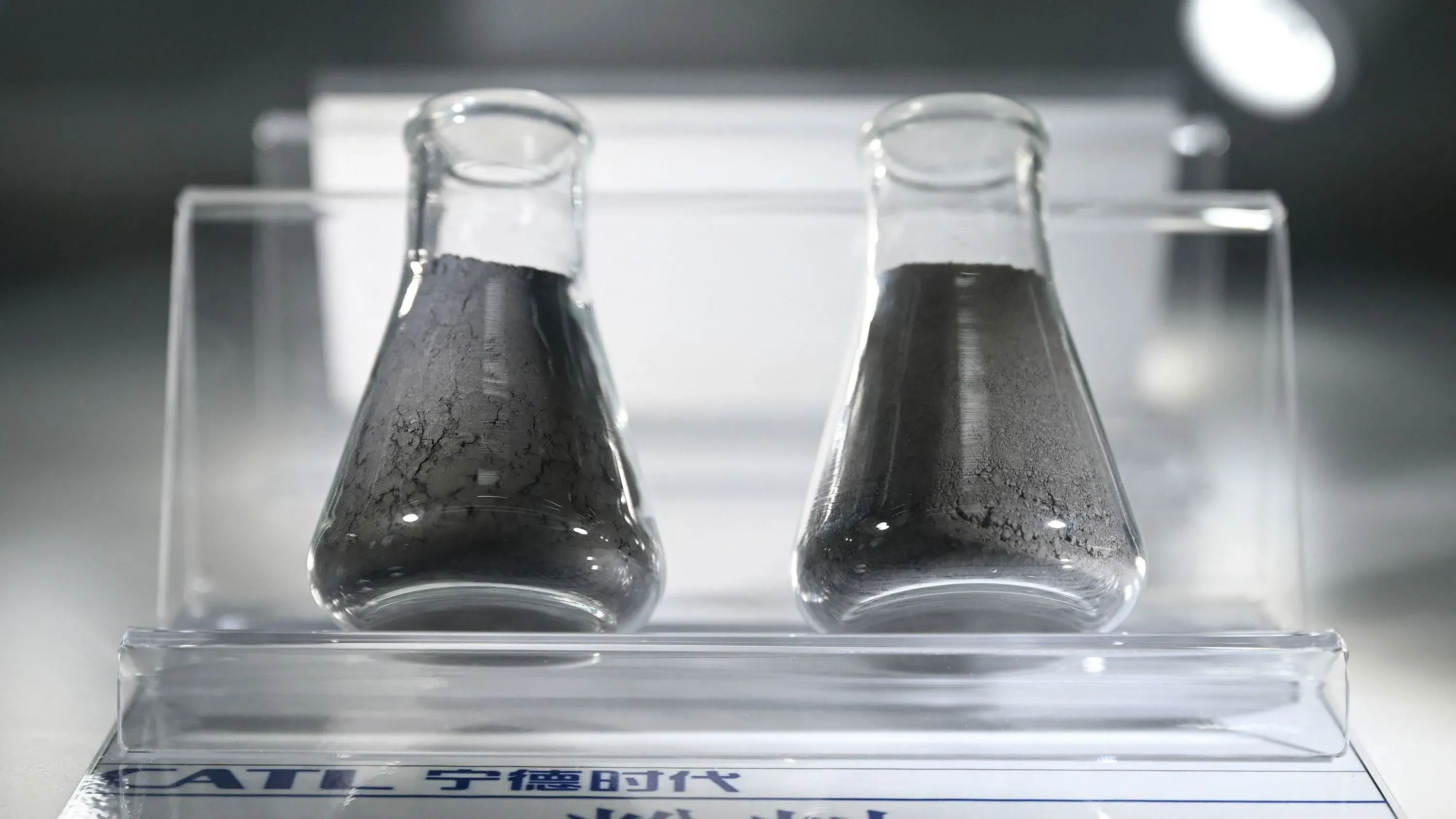 زجاجتان تحتويان على مسحوق الجرافيت، مما يبرز أهمية المادة في صناعة بطاريات السيارات الكهربائية في ظل التعريفات الجمركية الجديدة.