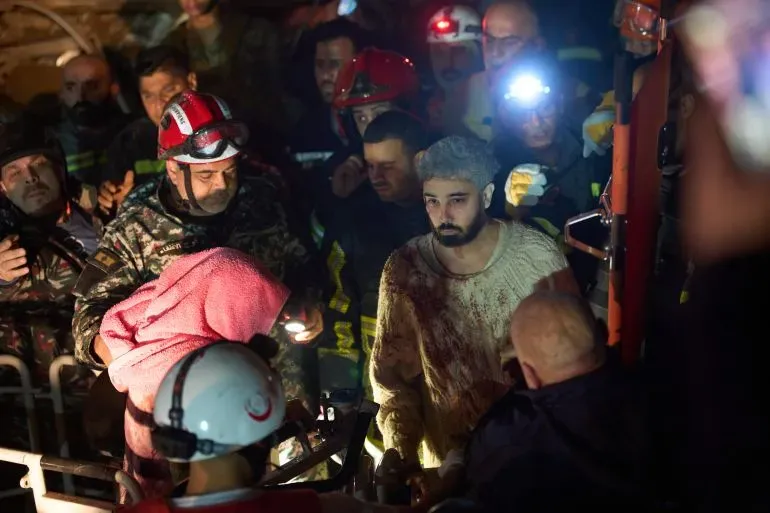 رجال إنقاذ يحيطون بشاب مصاب، مغطى بالدماء، بعد الهجمات الإسرائيلية في لبنان، حيث تظهر علامات الفوضى والذعر في المشهد.