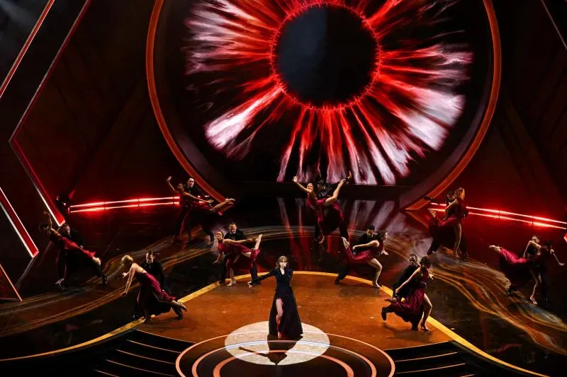 عرض موسيقي في مهرجان كوتشيلا، مع فنانة تؤدي على المسرح محاطة بمجموعة من الراقصين، وخلفية ملونة تعكس أجواء الحفل.