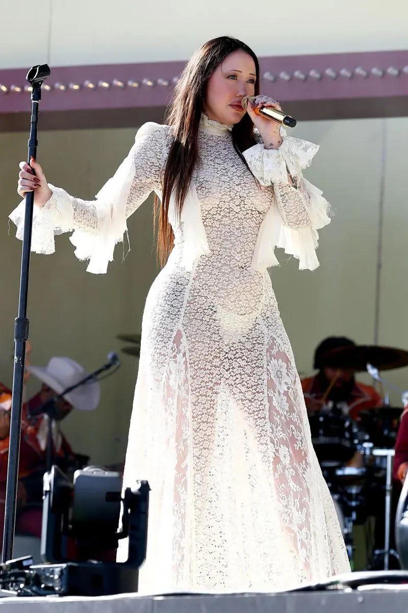 مغنية ترتدي فستاناً شفافاً مزيناً بالدانتيل، تؤدي على المسرح في مهرجان كوتشيلا، مع فرقة موسيقية في الخلفية.