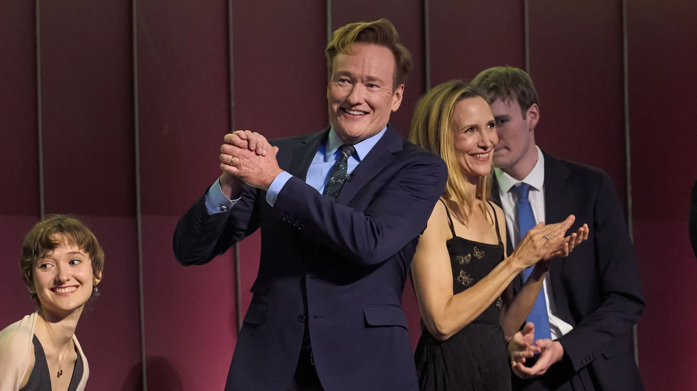 كونان أوبراين يتلقى جائزة مارك توين للفكاهة الأمريكية في مركز كينيدي، وسط تصفيق الحضور، مع تعبيرات الفرح والاحتفاء.