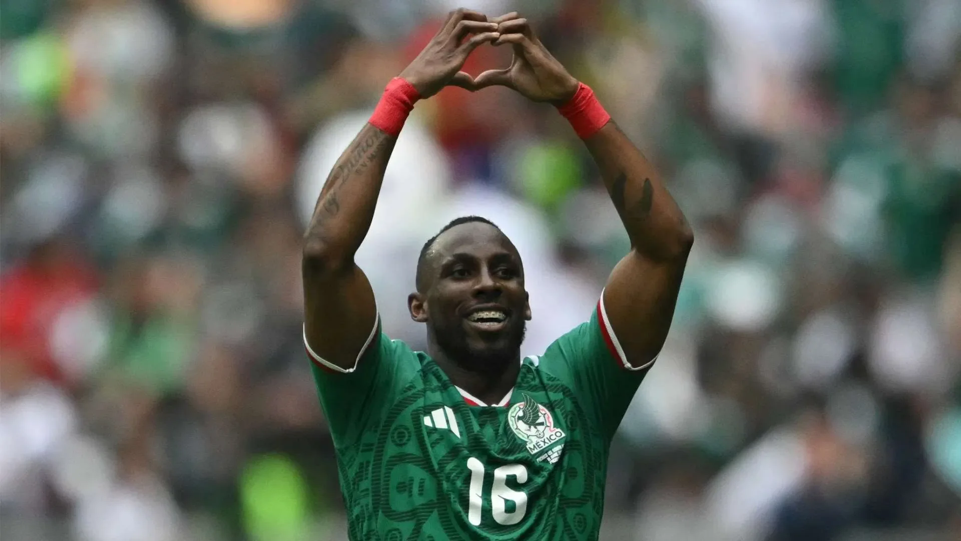 لاعب كرة قدم مكسيكي يرتدي الرقم 16 ويحتفل بحركة يدوية على شكل قلب خلال مباراة في كأس العالم CONCACAF.