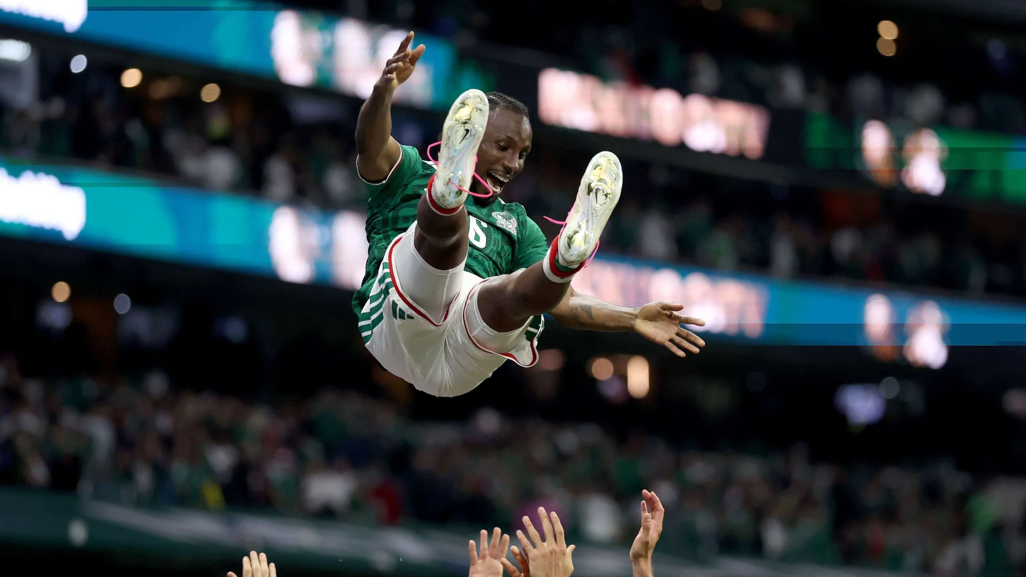 لاعب مكسيكي يحتفل بحماس في استاد كرة قدم خلال مونديال CONCACAF، مع جماهير في الخلفية.