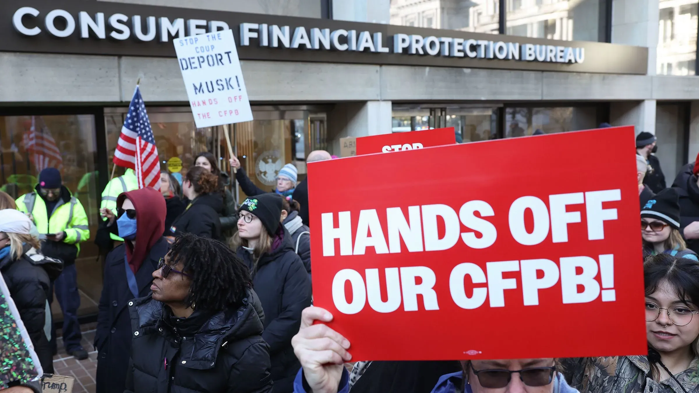 احتجاج أمام مكتب حماية المستهلك المالي، حيث يحمل المتظاهرون لافتات تدعو للحفاظ على الوكالة وسط محاولات تقليص عدد الموظفين.