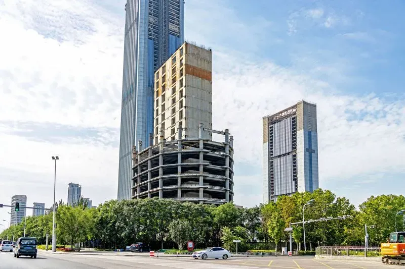 ناطحة سحاب غير مكتملة في تيانجين، تُظهر الهيكل الأساسي مع مبانٍ عالية محيطة، تشير إلى استئناف البناء بعد توقف طويل.